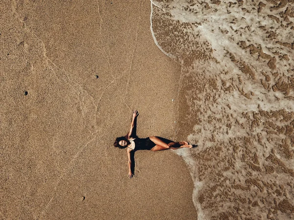 Widok z lotu ptaka top młoda kobieta, leżąc na plaży piasek i fale — Zdjęcie stockowe