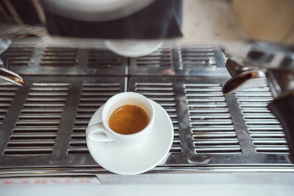 close-up view of glass cup with cappuccino and coffee machine