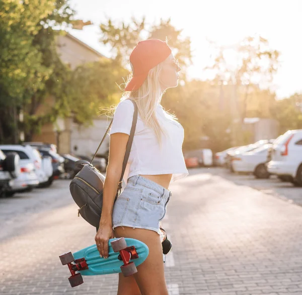 Jong meisje met een skateboard op een parkeerplaats. — Stockfoto