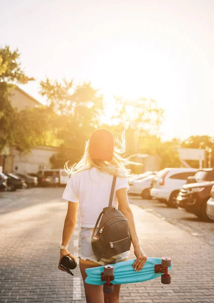 Jong meisje met een skateboard op een parkeerplaats. — Stockfoto