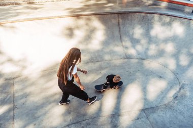 Genç anne küçük oğluna kaykay sürmeyi öğretiyor.