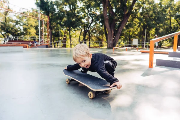 Petit garçon essayant de ramasser un skateboard — Photo