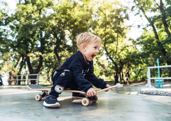 Jeune enfant assis dans le parc sur une planche à roulettes . — Photo