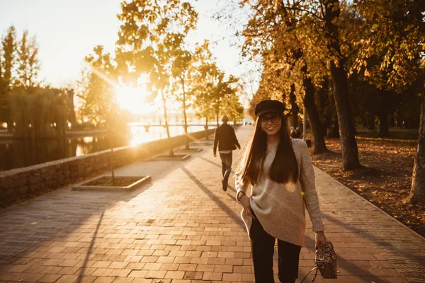 Attractive, young brunette with long hair walking autumn park.