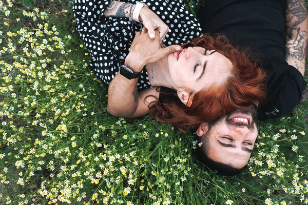 Casal jovem encontra-se no campo com margaridas . — Fotografia de Stock