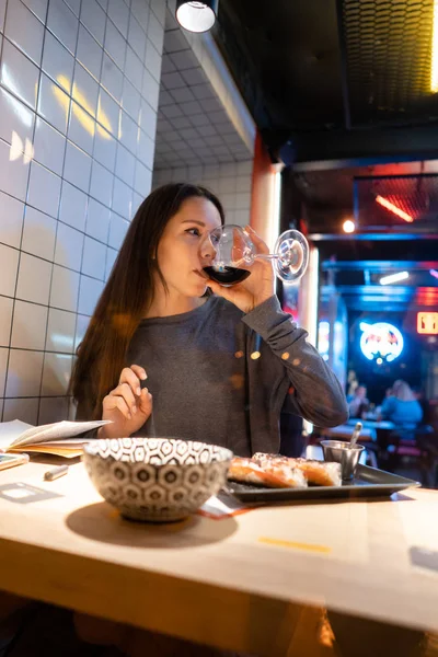 Молодая красивая брюнетка пьет вино в кафе — стоковое фото