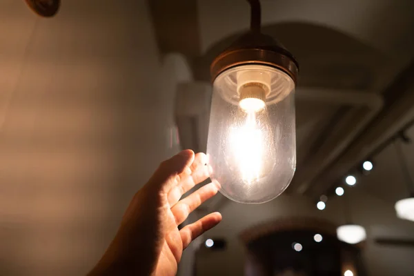 Hand reaching for a vintage light bulb. — Stock Photo, Image