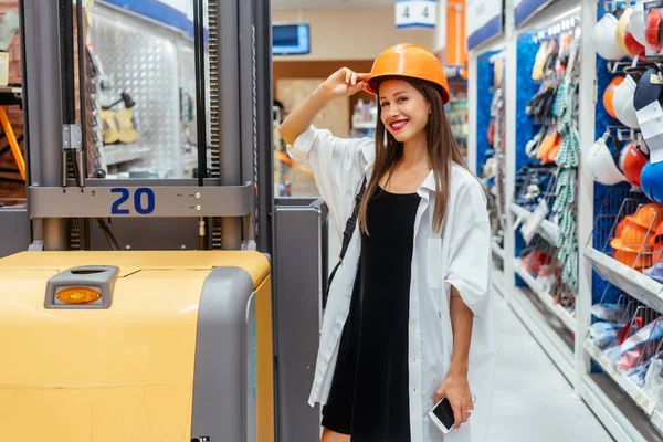 슈퍼마켓에서 주황색 건축용 헬멧을 쓴 여자, 배경 이 흐릿하다 — 스톡 사진