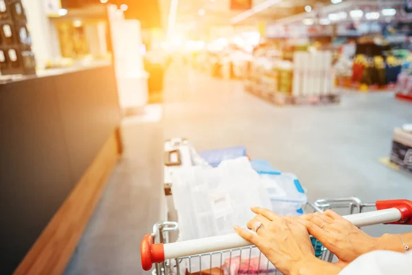 Menschliche Hand hautnah mit Einkaufswagen im Supermarkt — Stockfoto