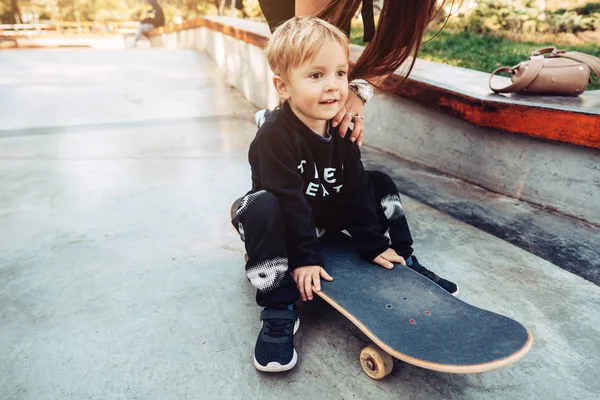 Молодой парень сидит в парке на скейтборде . — стоковое фото