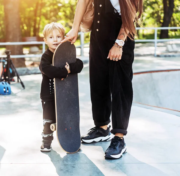 Маленький мальчик несет большой скейтборд снаружи — стоковое фото
