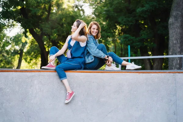 Dwie szczęśliwe młode dziewczyny siedzące w skate parku — Zdjęcie stockowe