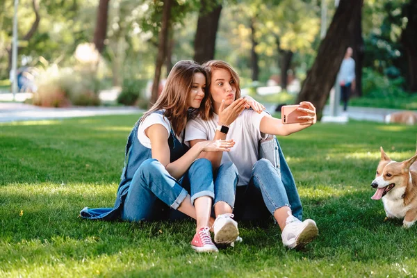 Två kvinnliga vän sitta i parken har en vila som ta en selfie — Stockfoto