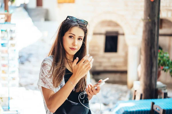 Ein Mädchen hält ein Handy in der Hand und posiert vor der Kamera. — Stockfoto