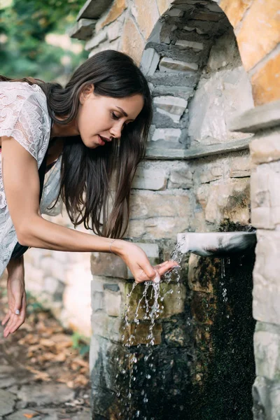 Beautiful, young girl drinks spring water outdoor — Stock Photo, Image