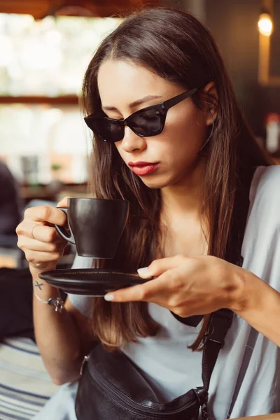 Hermosa joven bebe café en un café — Foto de Stock