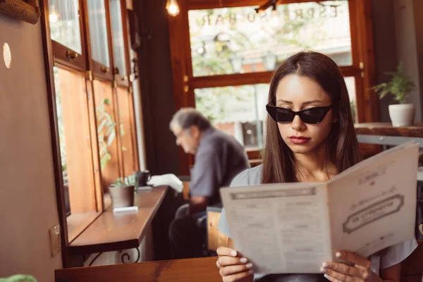 Привлекательная женщина в солнечных очках сидит в ресторане . — стоковое фото
