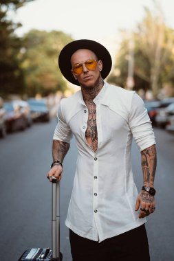 Karizmatik bir genç adam sokakta bir kamerada poz veriyor