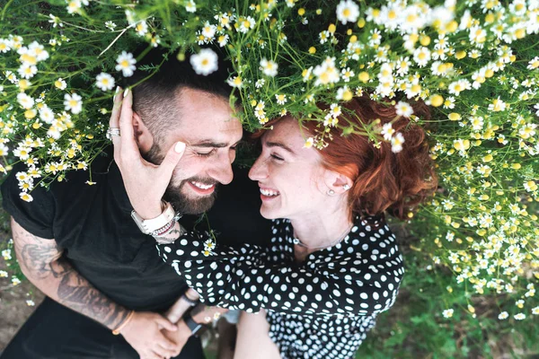 Junges Paar liegt mit Gänseblümchen auf dem Feld. — Stockfoto