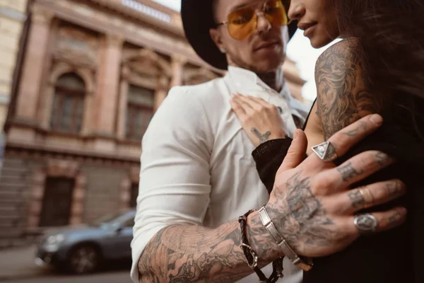 Les hommes main dans les tatouages et les bijoux embrasse une taille de filles . — Photo