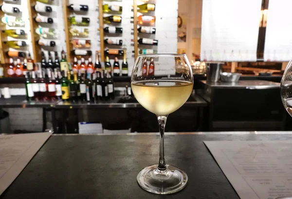 Verre à vin blanc sur une table en bois, fond de collection de bouteilles de vin — Photo