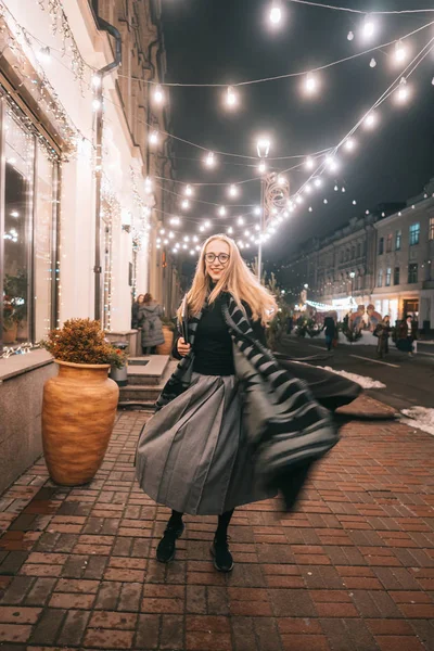 Sokakta dizüstü bilgisayarla poz veren genç bir kadın.