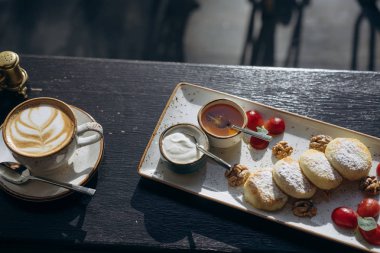 Süzme peynir ile ekşi krema, bir tepsi ve latte tatlım krep.
