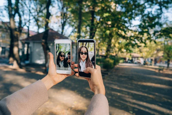 Menina bonita segura em suas mãos dois smartphones — Fotografia de Stock