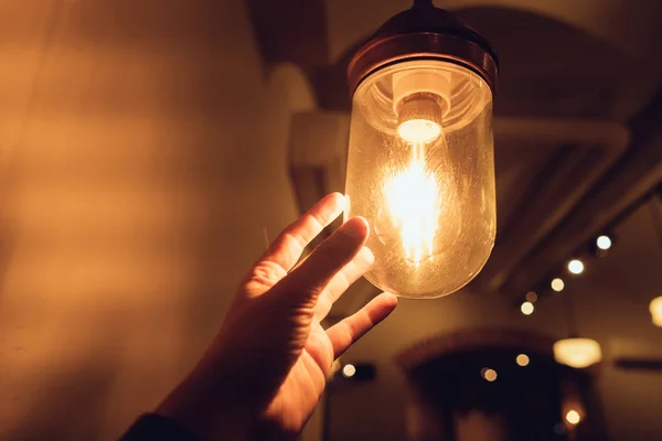 Hand reaching for a vintage light bulb. — Stock Photo, Image