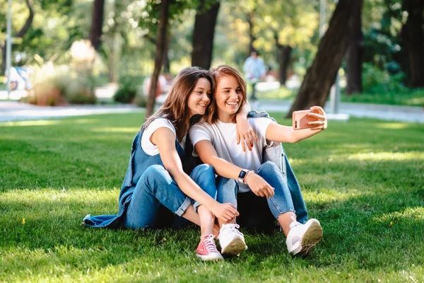 公園で座っている女性の 2 つの友人は、selfie を取る残りを持っています。 — ストック写真
