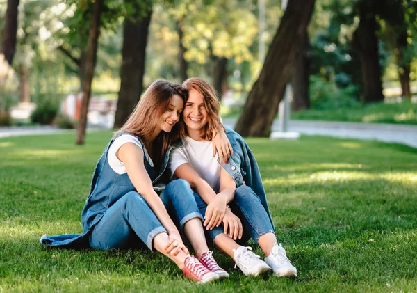 Due amici sono seduti sul prato verde nel parco . — Foto Stock