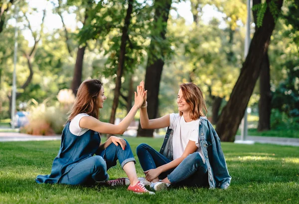 Szczęśliwy koleżanki, podnosząc ręce do góry dając piątkę w parku miejskim — Zdjęcie stockowe