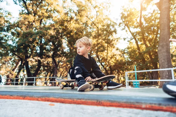 Jeune enfant assis dans le parc sur une planche à roulettes . — Photo