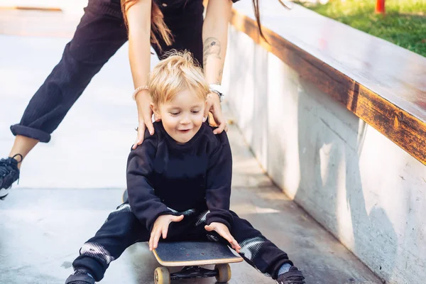年轻的母亲教她的小男孩骑滑板 — 图库照片