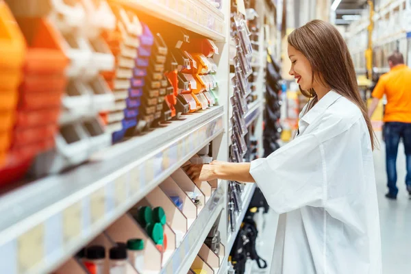 Frau wählt Kunststoffboxen in verschiedenen Farben für die Werkstatt — Stockfoto