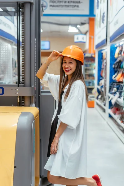 Kobieta w pomarańczowym hełmie budowlanym w tle rozmycia supermarketu — Zdjęcie stockowe