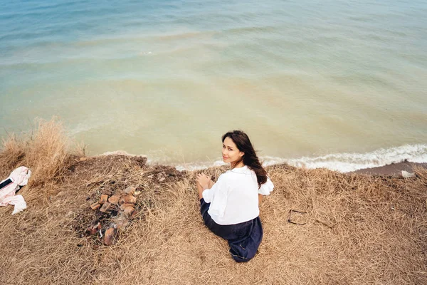 Atrakcyjna kobieta w letniej spódnicy i koszuli siedzi na brzegu — Zdjęcie stockowe