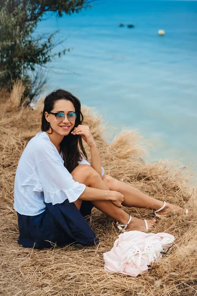 Yazlık etekli ve gömlekli çekici bir kadın sahilde oturuyor. — Stok fotoğraf