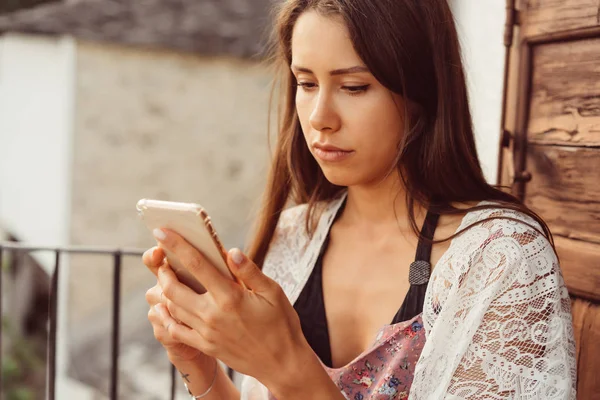 Bir telefon ile çekici kadın balkonda oturuyor. — Stok fotoğraf