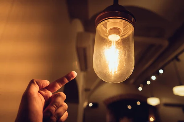 Hand reaching for a vintage light bulb. — Stock Photo, Image