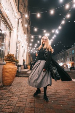 Sokakta dizüstü bilgisayarla poz veren genç bir kadın.