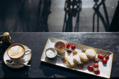 Süzme peynir ile ekşi krema, bir tepsi ve latte tatlım krep.
