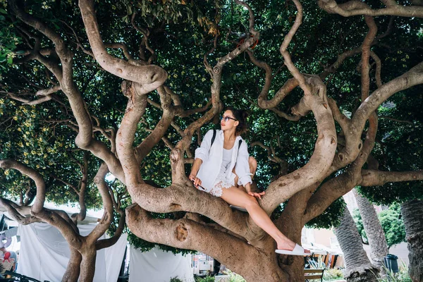 Güzel kadın bir ağaçta oturuyor. Bahar zamanı — Stok fotoğraf