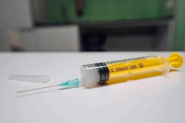 Una jeringa médica amarilla única con aguja acostada —  Fotos de Stock