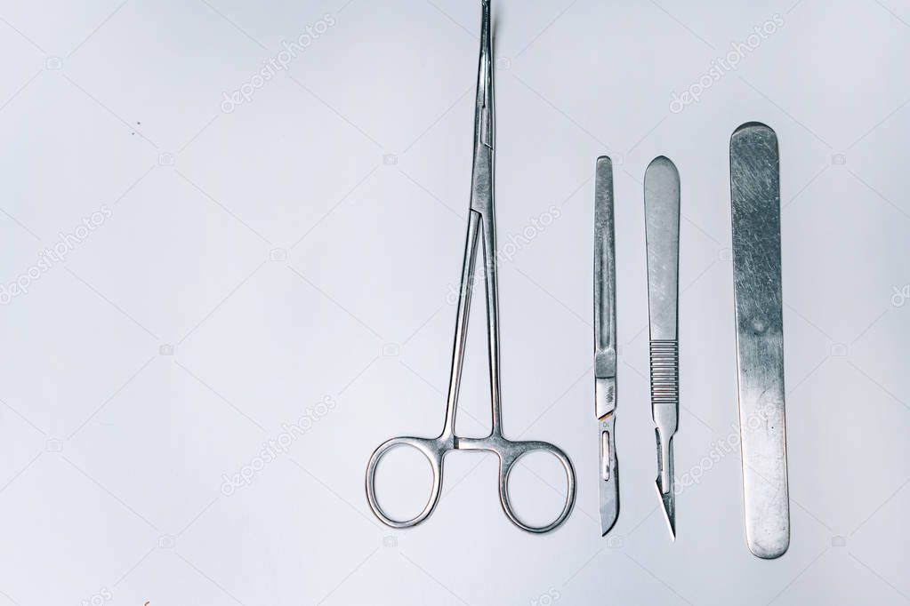 Scapula for throat, two scalpels and clamp on a light background