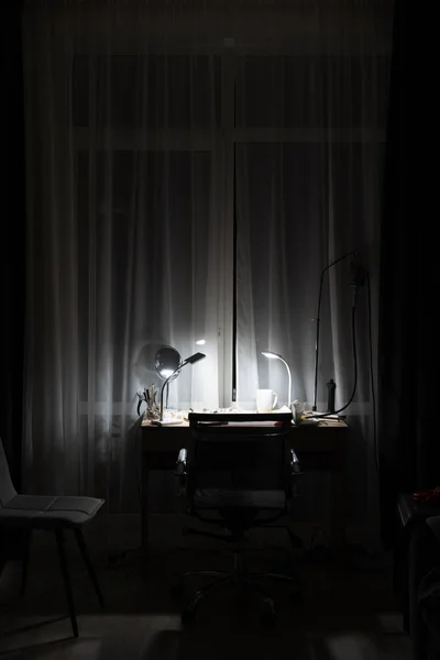 Рабочее место в комнате с лампой на — стоковое фото
