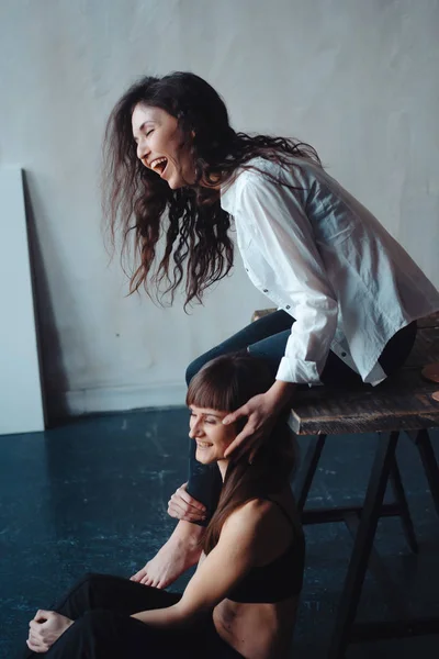 Duas meninas estão posando para a câmera, uma sentada em uma cadeira, outra no chão — Fotografia de Stock
