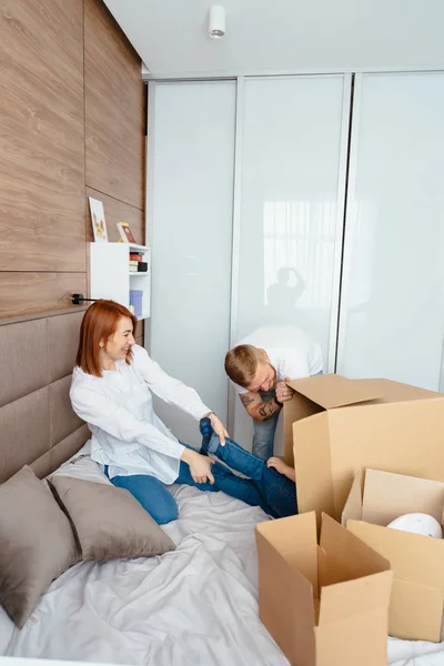 Papá mamá e hijo pequeño juegan en el dormitorio con cajas de papel — Foto de Stock