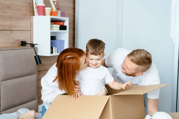 Papá mamá e hijo pequeño juegan en el dormitorio con cajas de papel — Foto de Stock