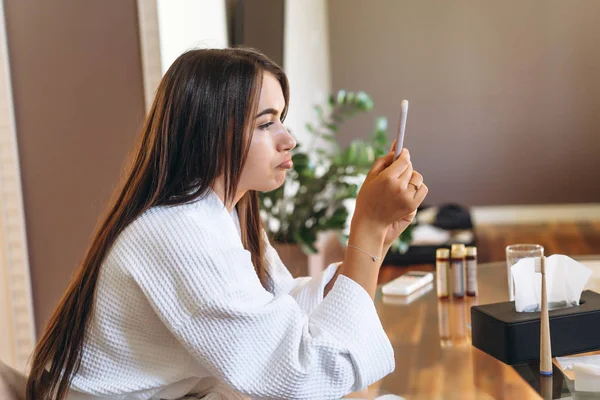 Young woman in bathrobe in hotel room using mobile phone — Stock Photo, Image